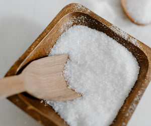 bowl of white salt with wooden spoon, which is better sugar or salt scrub?