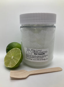 a cut lime, and a whole lime, and a 15 oz clear plastic jar of sea salt scrub with wooden spoon