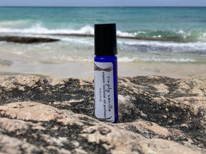 Non-toxic Simply Vanilla essential oil perfume bottle on a beach, highlighting clean, natural fragrance made without synthetic ingredients.