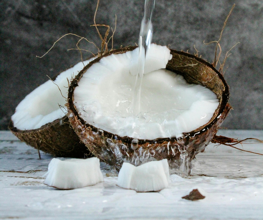 Coconut oil being poured into a fresh coconut shell – a natural ingredient used in aluminum free and baking soda free deodorant for sensitive skin.