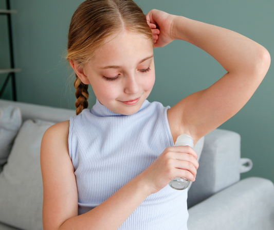 tween girl applying organic deodorant under her arm