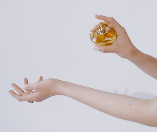 person spraying non toxic perfume from a perfume bottle onto their wrist