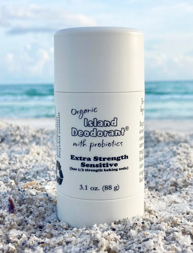 Extra strength sensitive organic deodorant, in white plastic twist up container, on the beach in front of the ocean