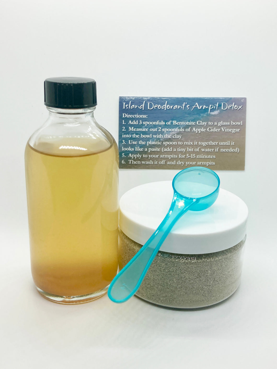 image of armpit detox kit, with 3.6 oz apple cidar vinegar in glass bottle, 6 oz of bentonite clay in a plastic container, measuring spoon, and instruction card