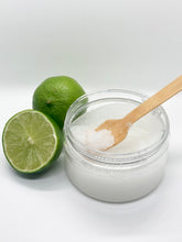 a cut lime, and a whole lime, and a 5 oz clear plastic jar of sea salt scrub with wooden spoon