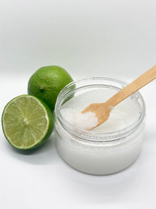 a cut lime, and a whole lime, and a 5 oz clear plastic jar of sea salt scrub with wooden spoon